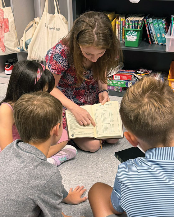 a woman reading a bible to kids