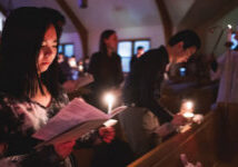 dark in church with lit candles woman and families in church pews Easter