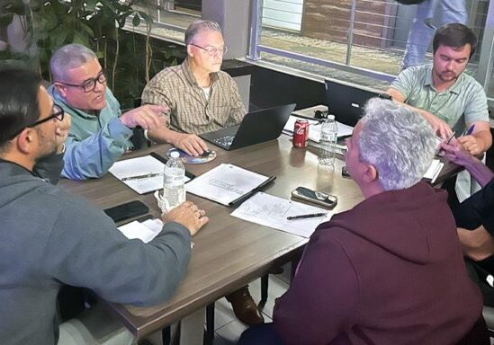 6 men chatting around a table