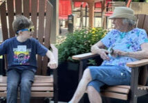 elderly woman and young man sitting on chairs outside talking