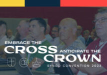 cross and crown logo with delegates at convention in background