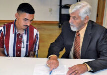 a gray haired man showing a young man some paperwork
