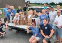 Church members pose around pickup truck filled with grocery bags of food