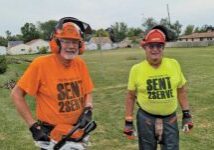 two men cutting down trees wearing safety equipment and send 2 serve shirts