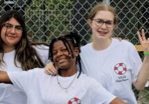 three female teenagers posing for a photo wearing white tshirts